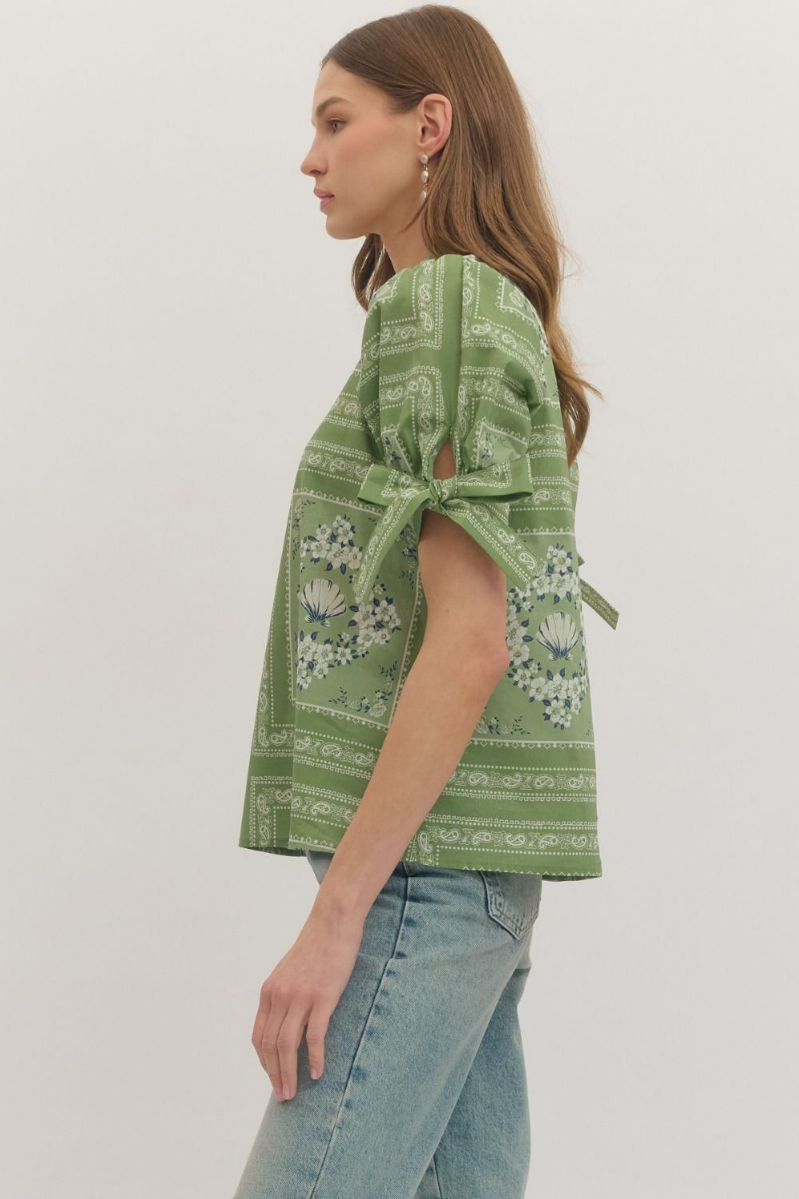 Woman wearing a green patterned top with a white background