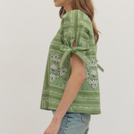 Woman wearing a green patterned top with a white background