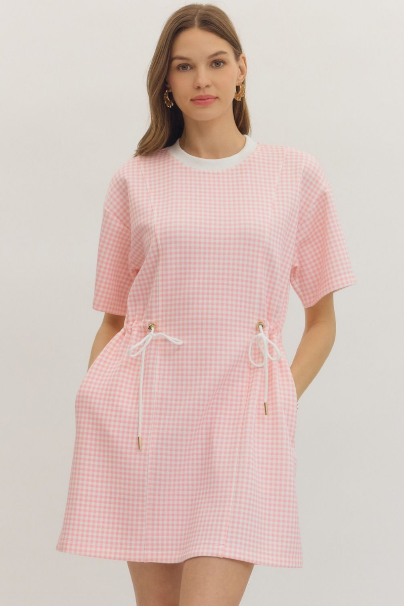 Woman wearing a pink checkered dress on a plain background