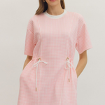 Woman wearing a pink checkered dress on a plain background