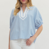 Woman wearing a blue and white striped blouse with a plain background