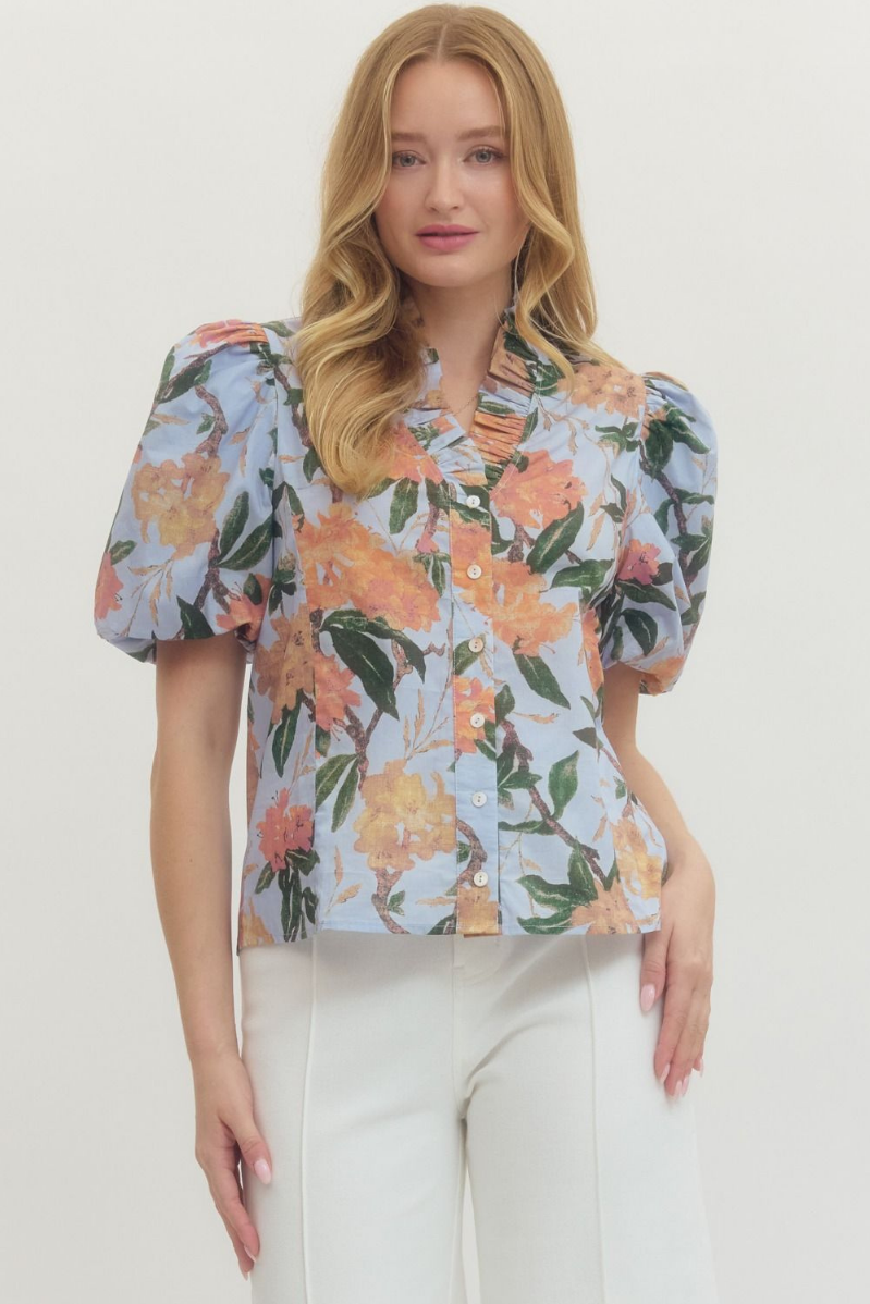 Woman wearing a floral blouse with puff sleeves against a white background