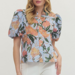 Woman wearing a floral blouse with puff sleeves against a white background