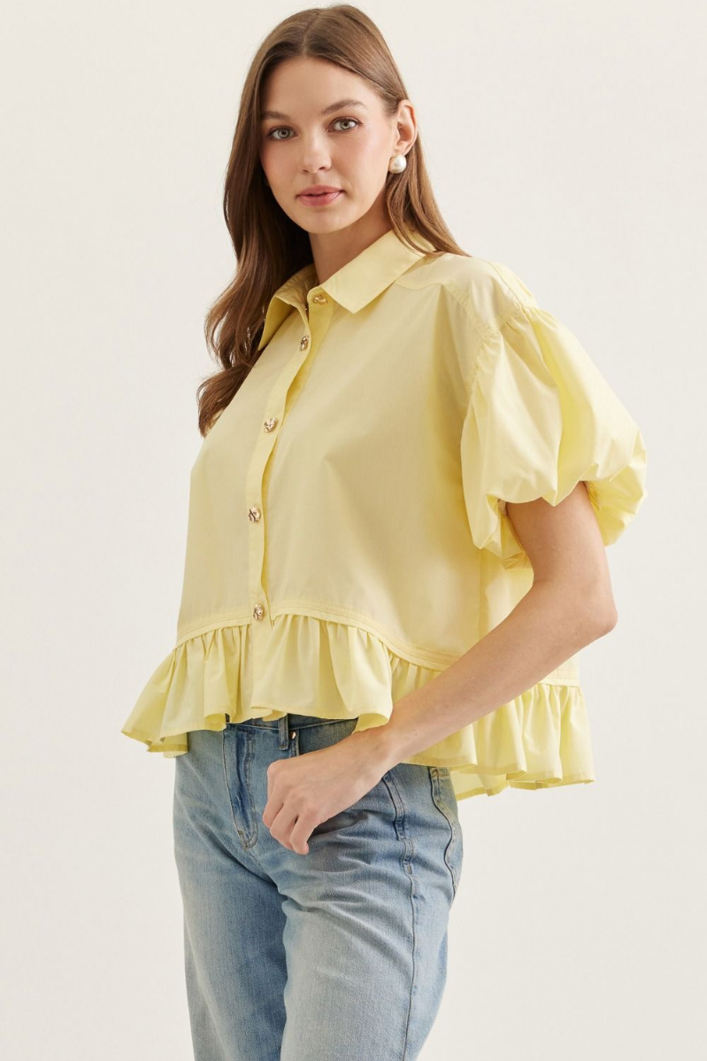 Woman wearing a yellow blouse with ruffled sleeves and hem on a white background