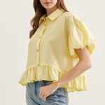 Woman wearing a yellow blouse with ruffled sleeves and hem on a white background
