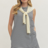 Woman wearing a striped dress with a yellow scarf on a plain background