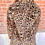 Person wearing a leopard print coat with a brick wall background