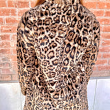 Person wearing a leopard print coat with a brick wall background