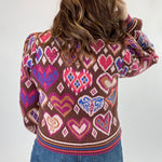 Person wearing a sweater with heart pattern on a plain background