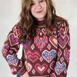 Woman wearing a patterned sweater with hearts and abstract designs on a plain background