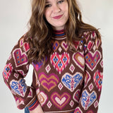 Woman wearing a patterned sweater with hearts and abstract designs on a plain background