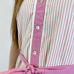 Close-up of a person wearing a striped shirt with a pink tie against a white background