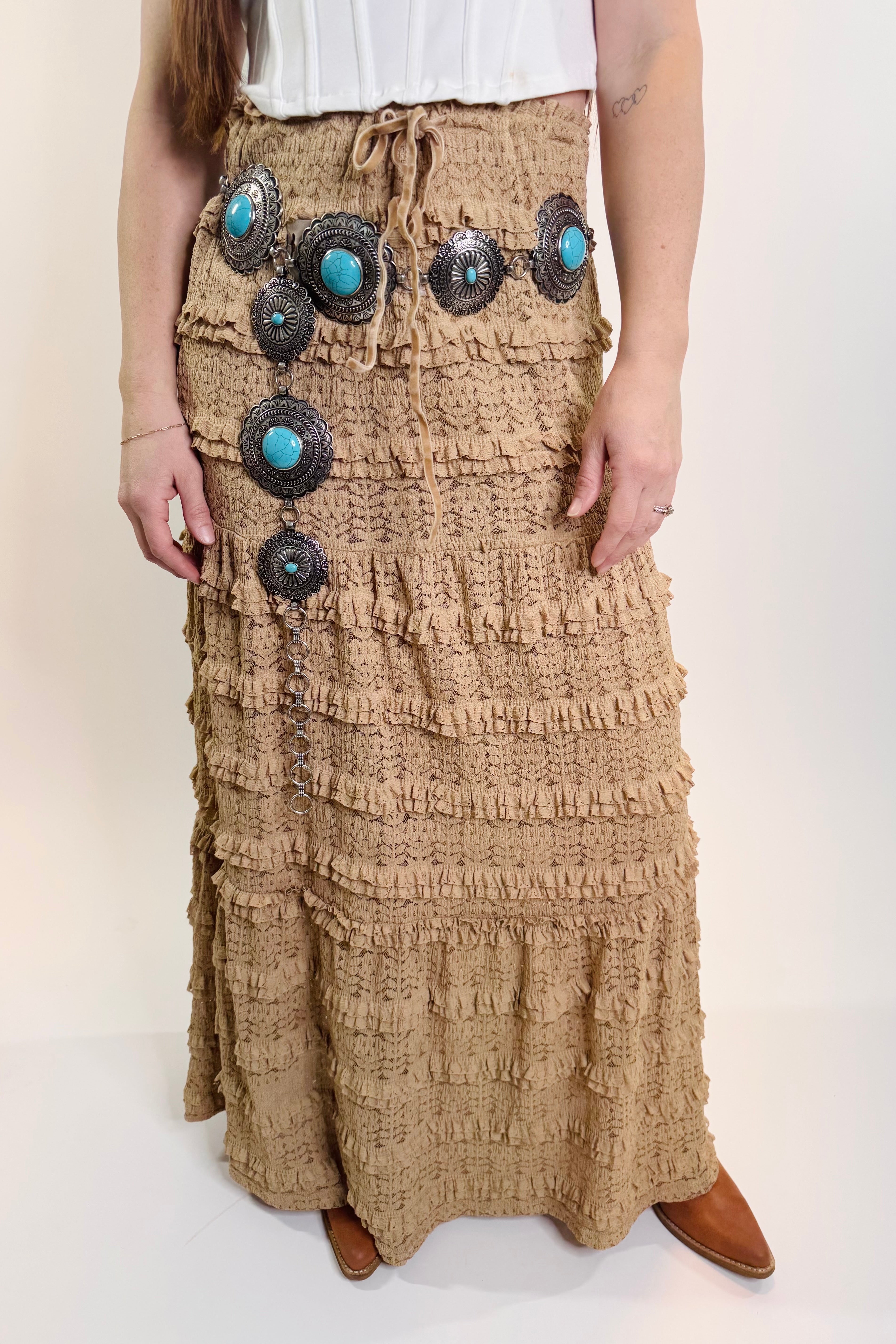 Person wearing a long, textured brown skirt with decorative buttons on a plain background