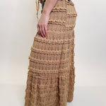 Person wearing a long, textured beige skirt on a white background
