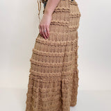 Person wearing a long, textured beige skirt on a white background