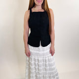 Woman wearing a black top and white patterned skirt on a plain background