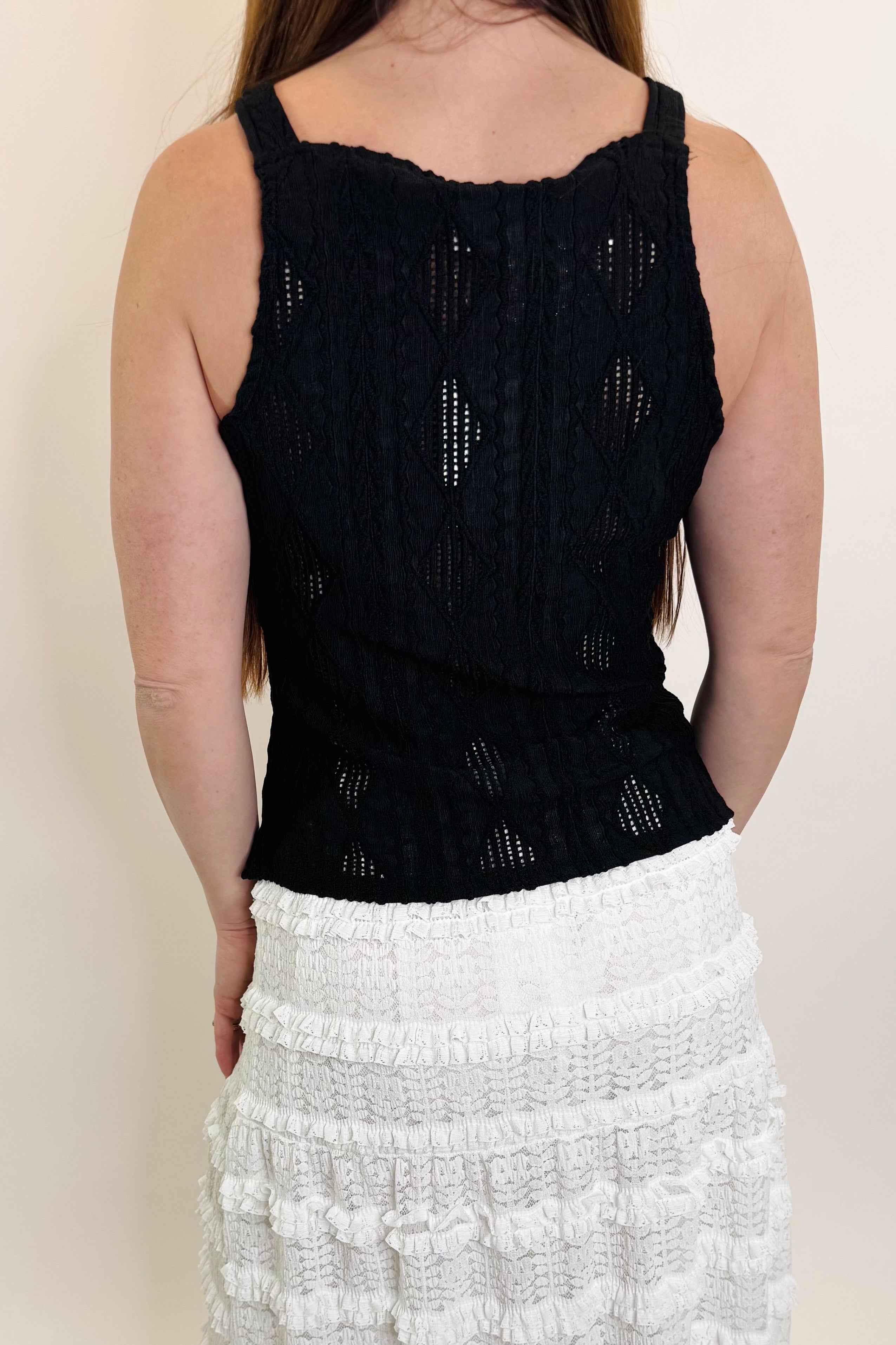 Person wearing a black sleeveless top and white skirt on a plain background