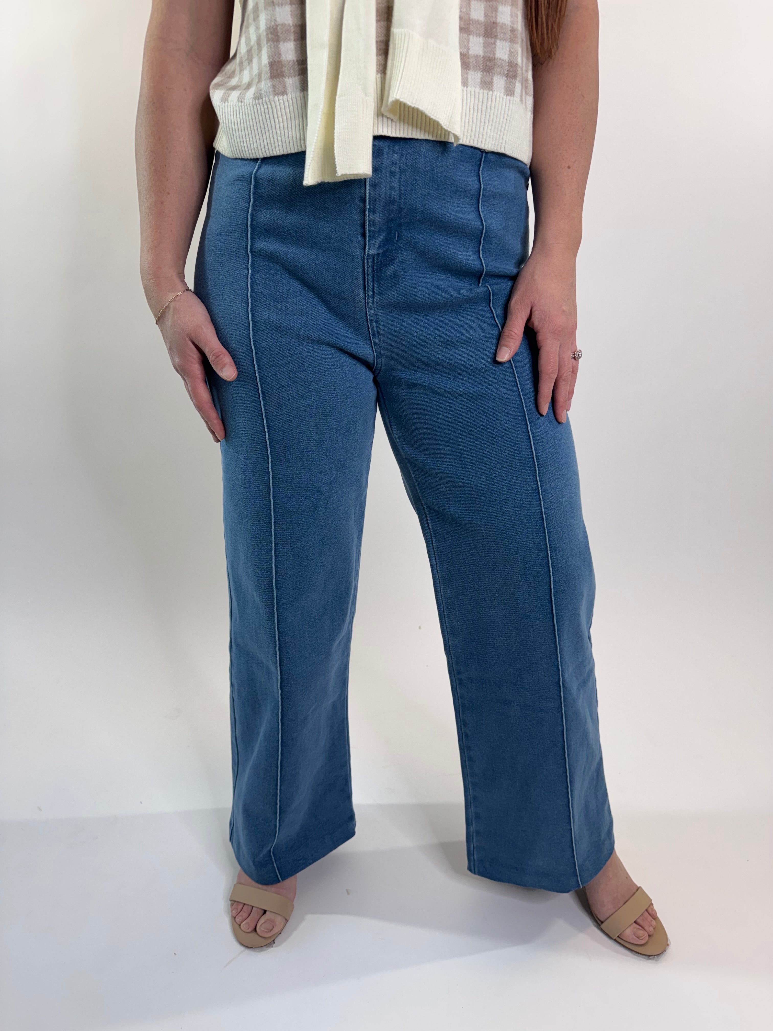 Person wearing blue jeans standing against a white wall