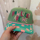 Green cap with colorful text held by a hand against a patterned background