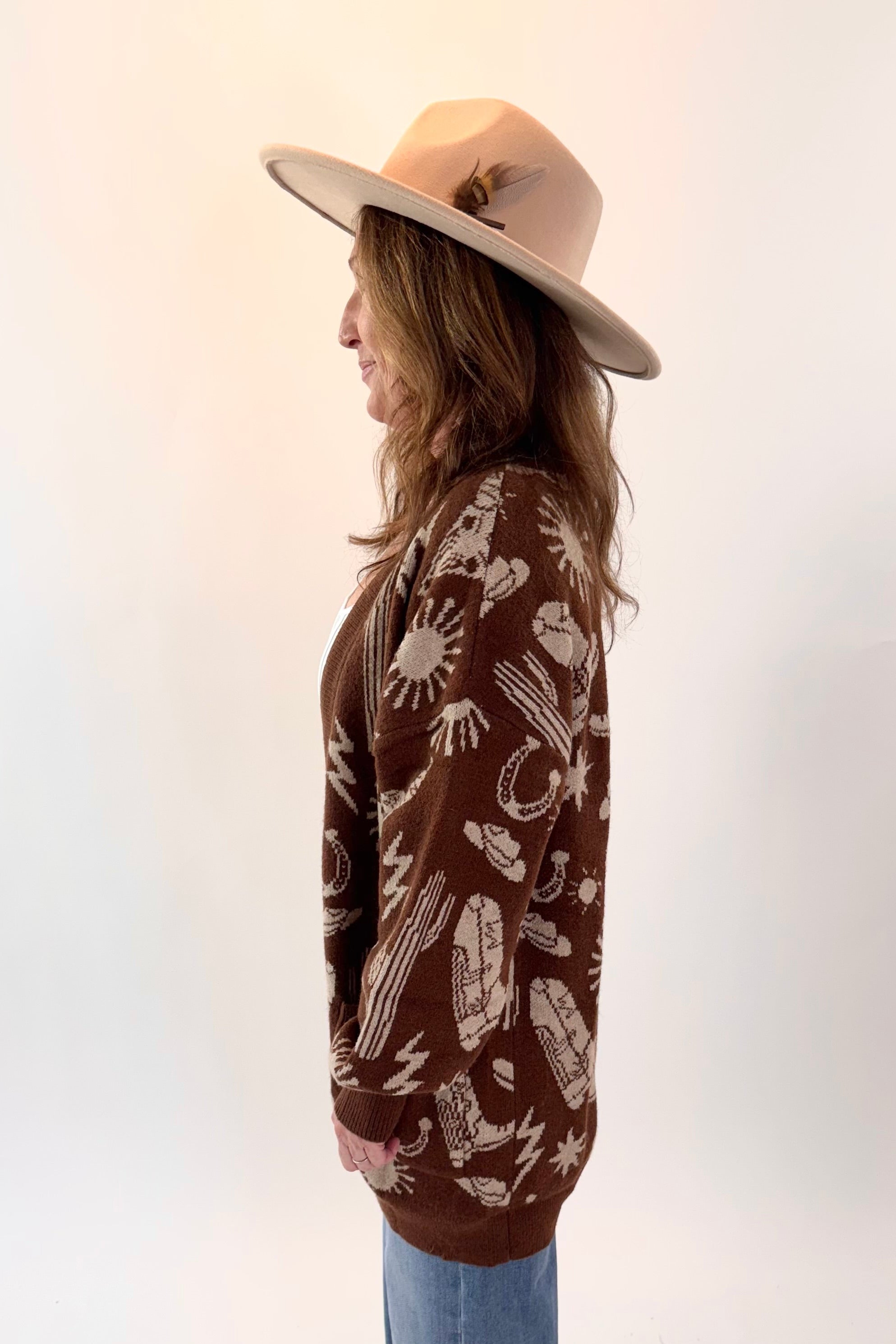 Person wearing a brown patterned sweater and beige hat on a white background