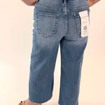 Person wearing blue jeans with a tag on a plain background