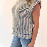 Person wearing a sleeveless striped top and jeans on a plain background