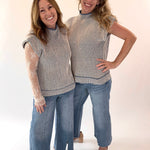 Two women wearing matching striped tops and jeans on a white background