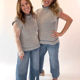 Two women wearing matching striped tops and jeans on a white background