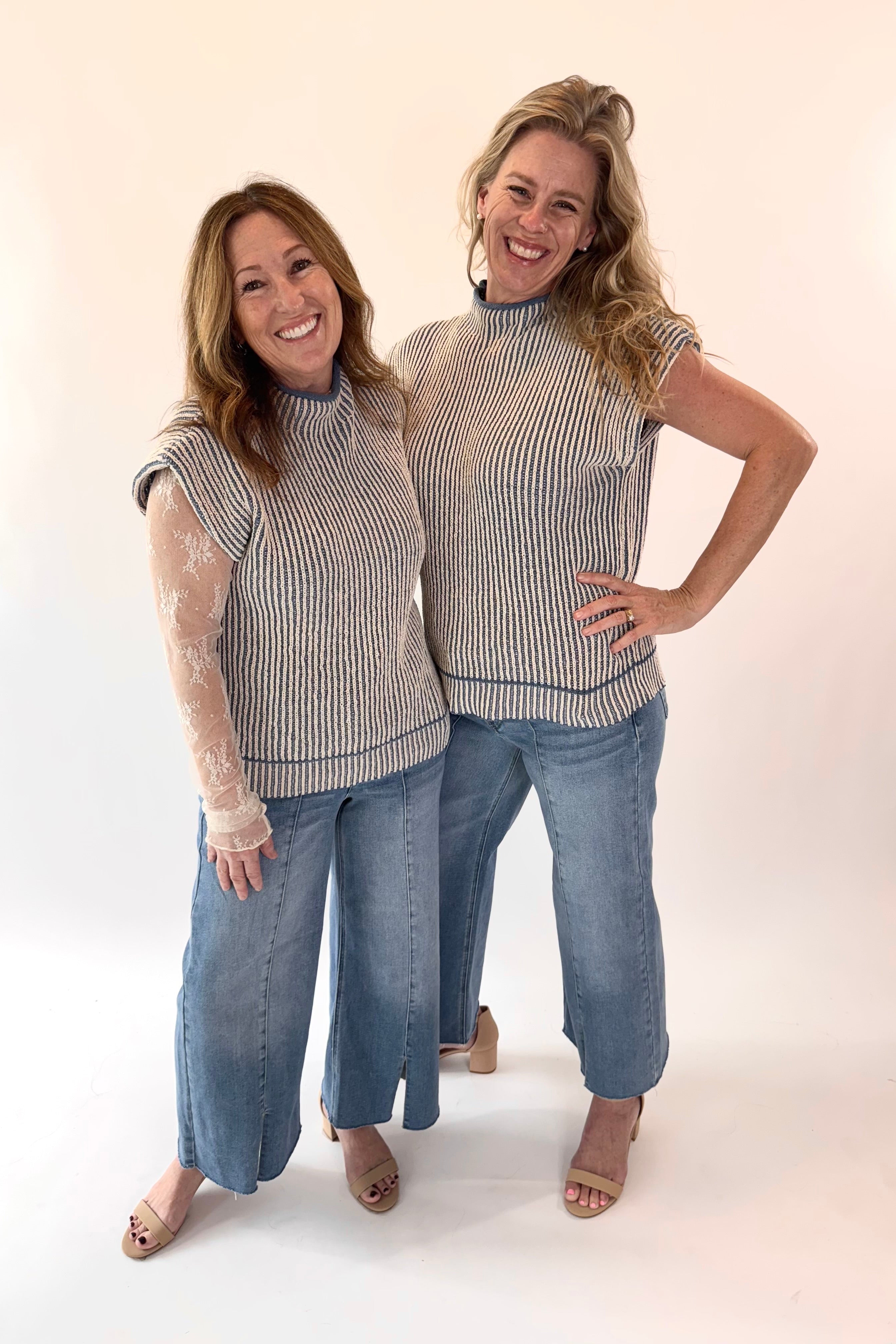 Two women wearing matching striped tops and jeans on a white background