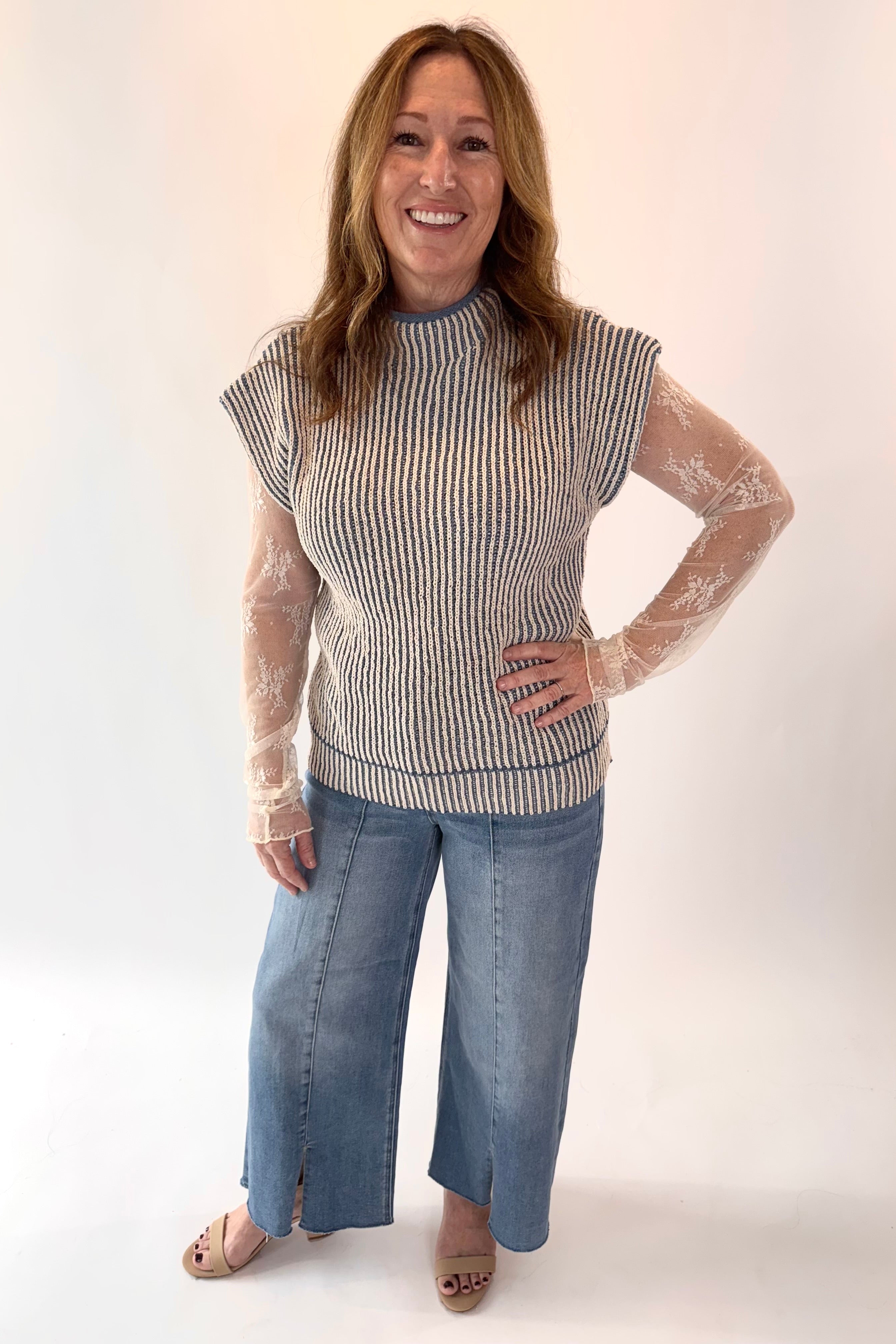 Woman wearing a striped sleeveless top and jeans on a white background