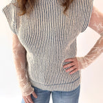 Person wearing a striped sweater with sheer sleeves against a white background