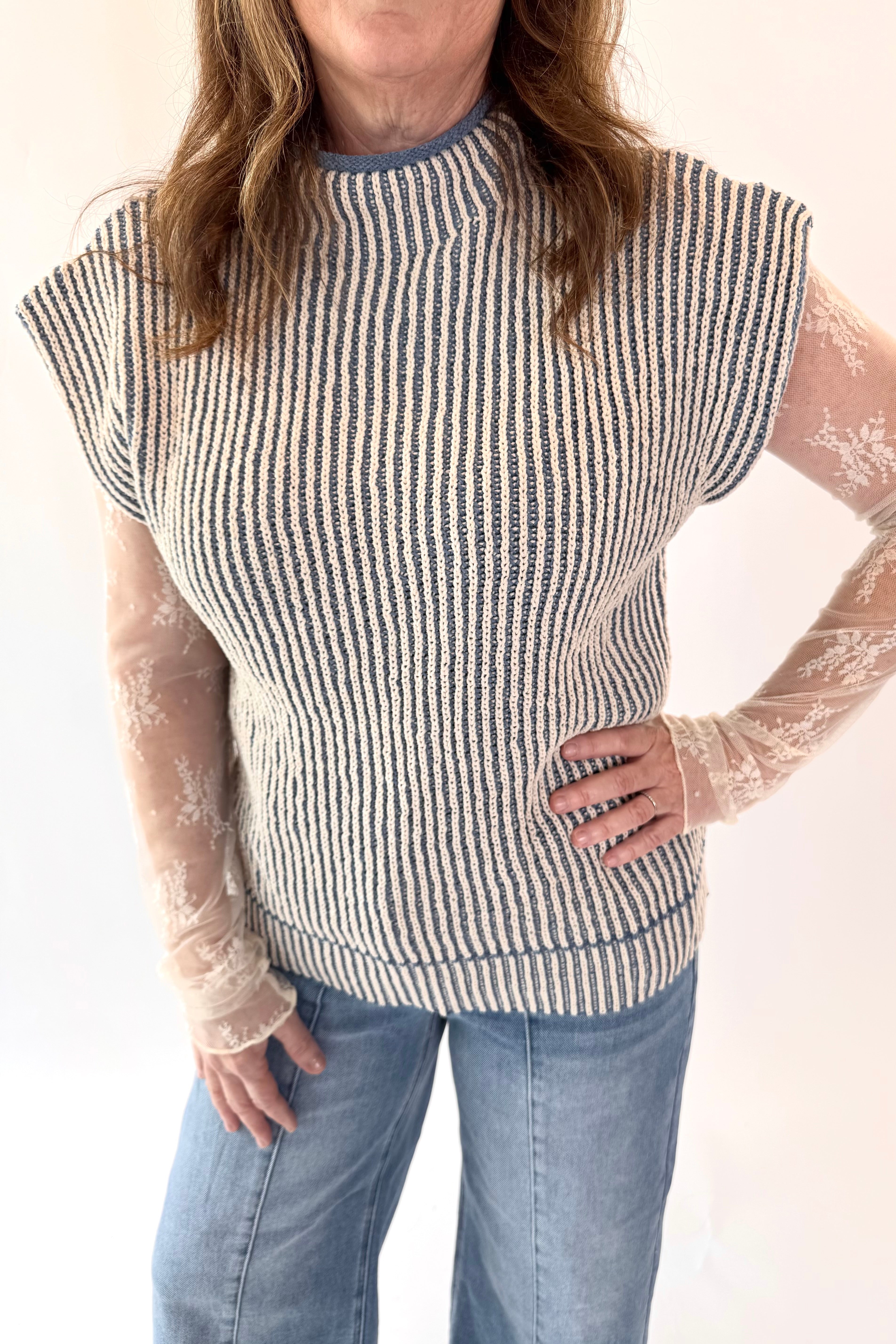 Person wearing a striped sweater with sheer sleeves against a white background