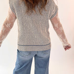 Person wearing a striped shirt with sheer sleeves and blue jeans on a white background