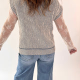 Person wearing a striped shirt with sheer sleeves and blue jeans on a white background