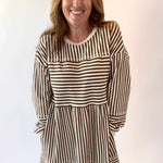 Woman wearing a brown and white striped dress against a plain background