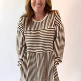 Woman wearing a brown and white striped dress against a plain background