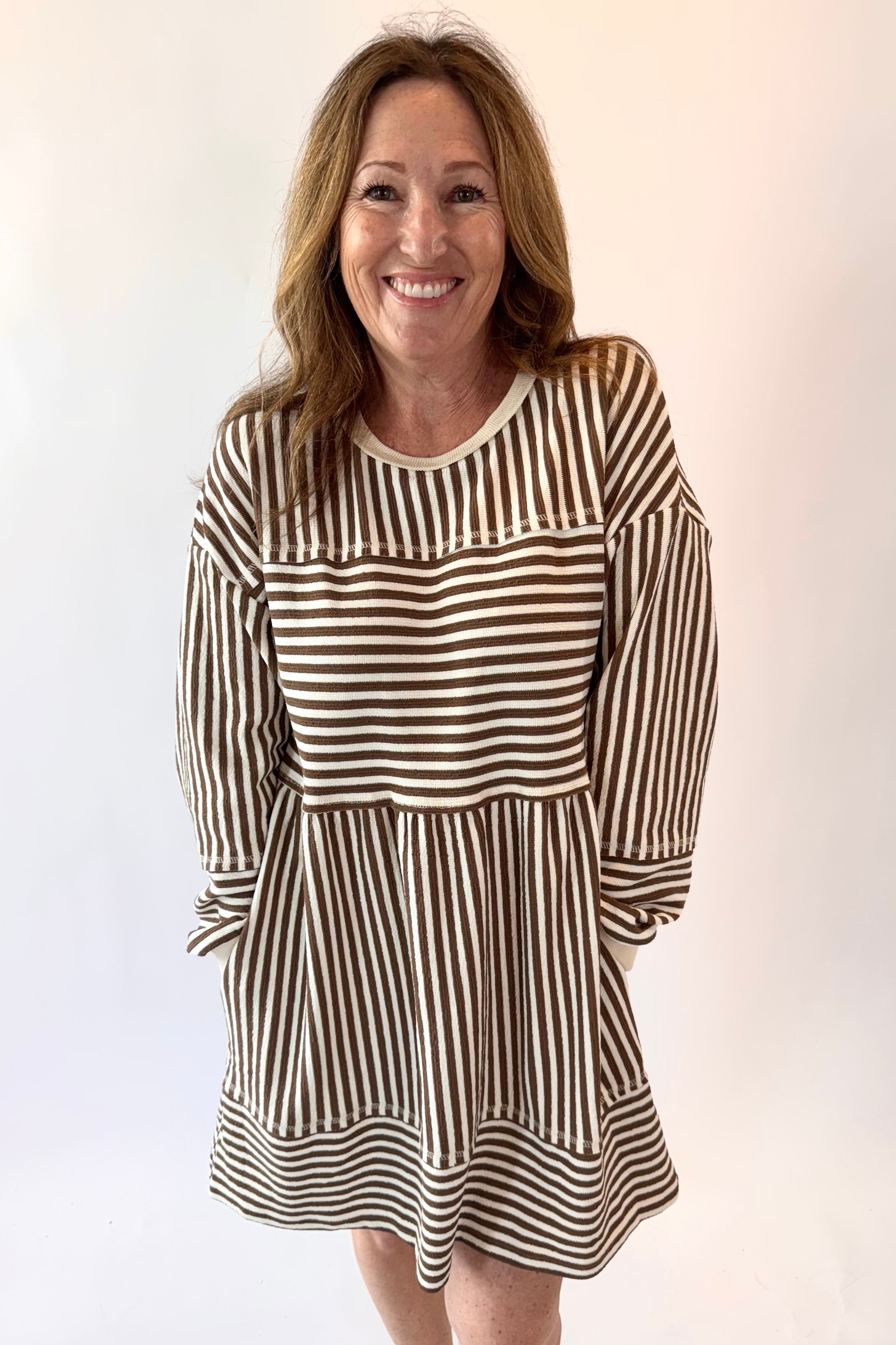 Woman wearing a brown and white striped dress against a plain background