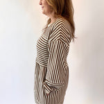 Woman wearing a black and white striped dress against a plain background
