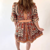 Person wearing a patterned dress with a backless design on a white background