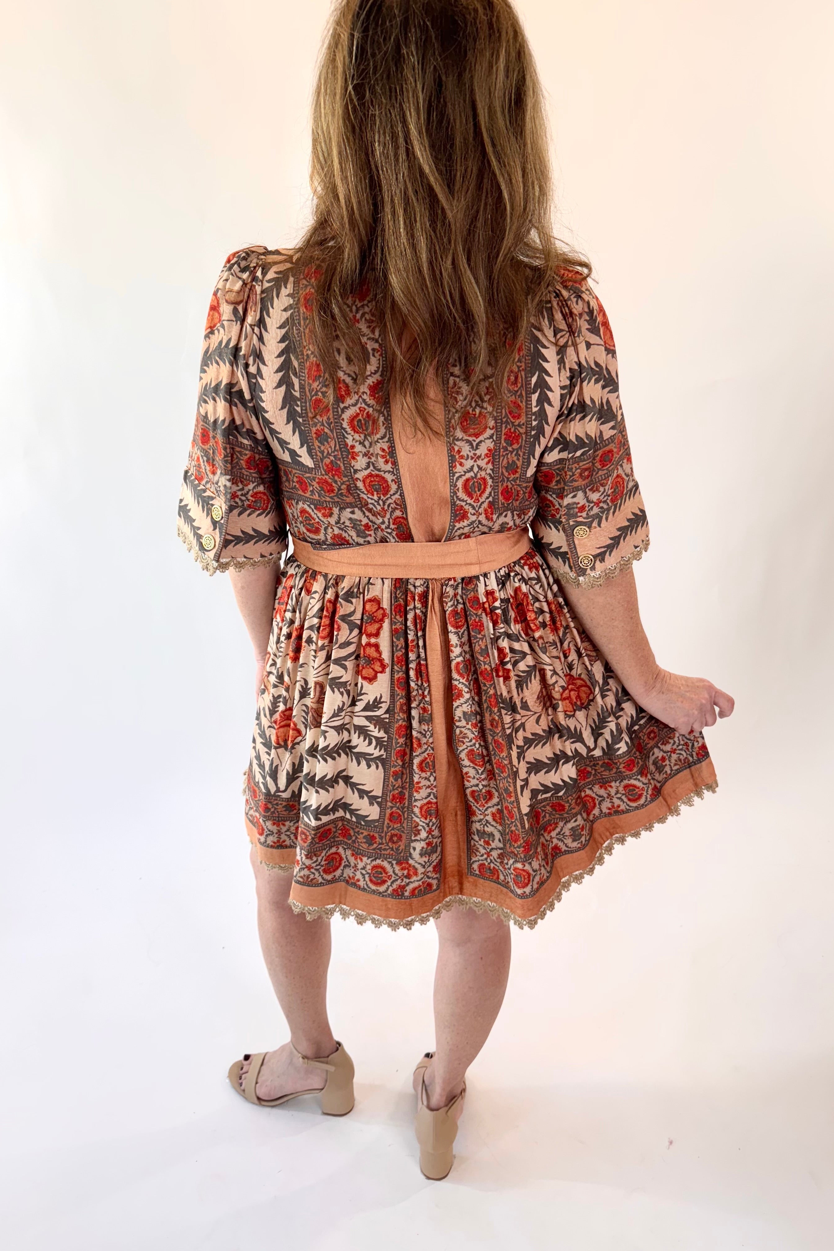 Person wearing a patterned dress with a backless design on a white background