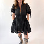 Woman wearing a black dress with lace details and gray boots on a white background