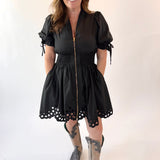 Woman wearing a black dress with lace details and gray boots on a white background