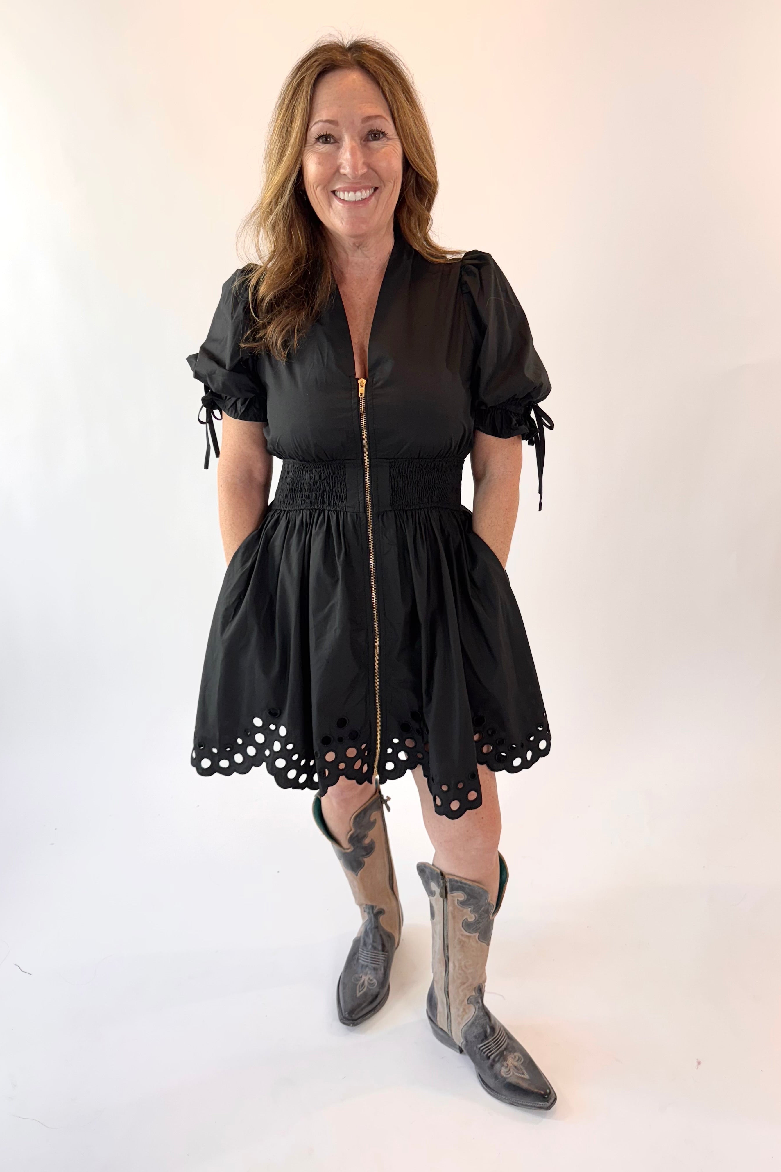 Woman wearing a black dress with lace details and gray boots on a white background