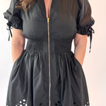 Black dress with puff sleeves and eyelet hem on a plain background