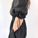 Black dress with puff sleeves and cut-out back on a white background
