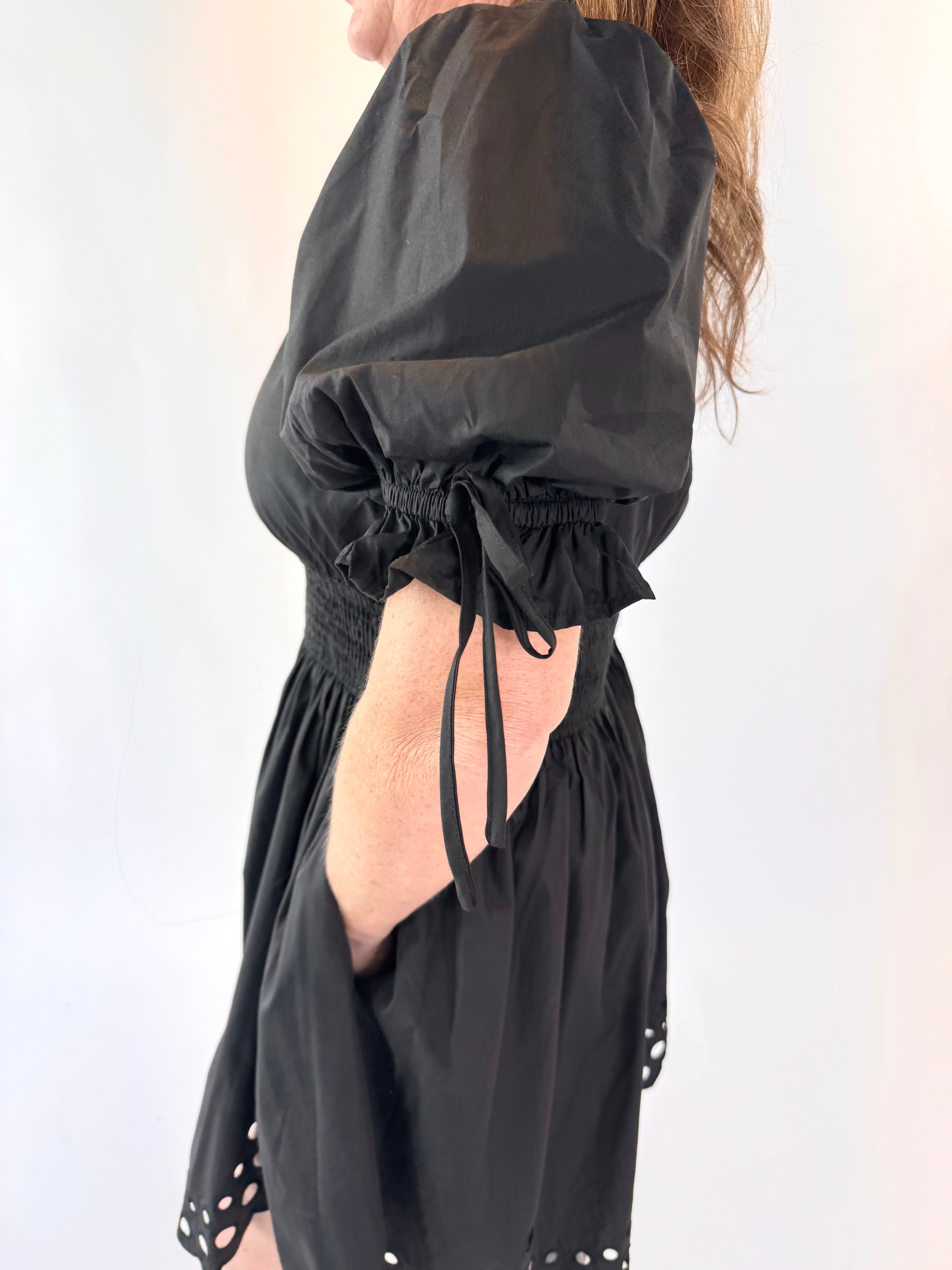 Black dress with puff sleeves and cut-out back on a white background