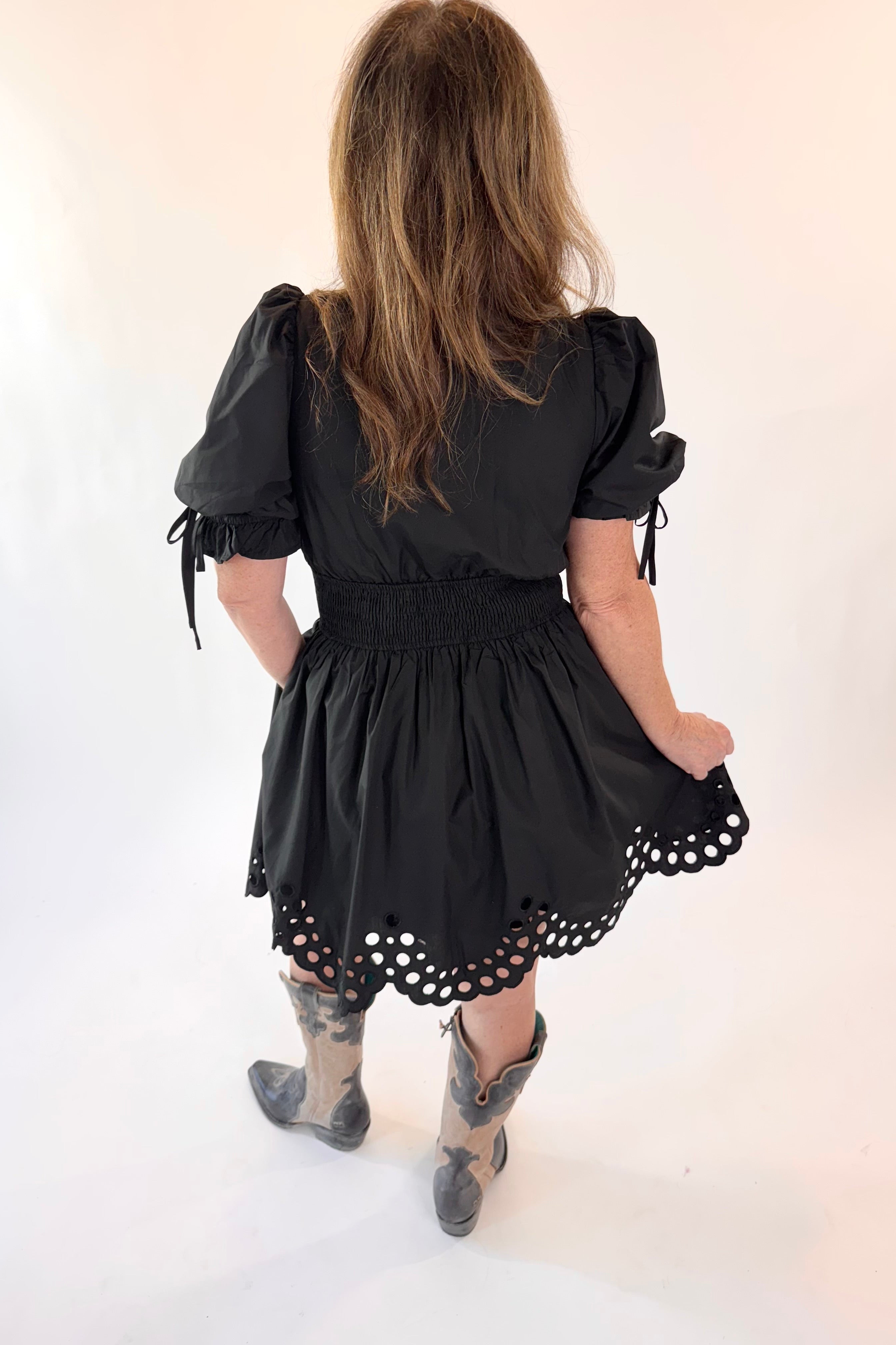 Child wearing a black dress with puff sleeves and lace details on a white background