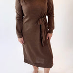 Woman wearing a brown dress with a tie waist on a white background