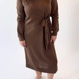 Woman wearing a brown dress with a tie waist on a white background