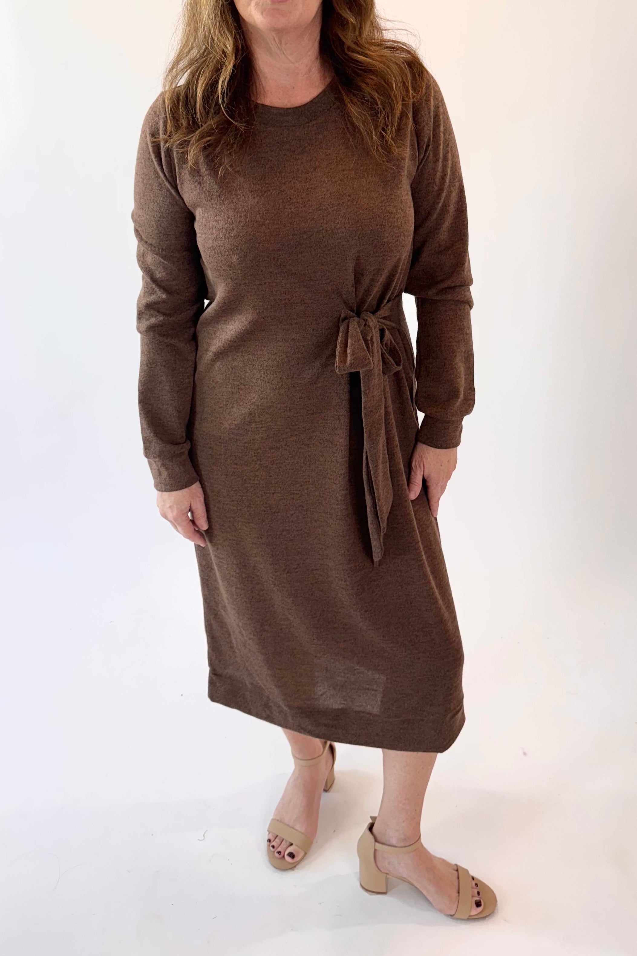 Woman wearing a brown dress with a tie waist on a white background